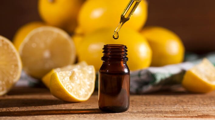 Lemon essential oil and lemon fruits on wooden background