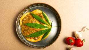 Weed leaf sitting on sausage and eggs in a cooking pot