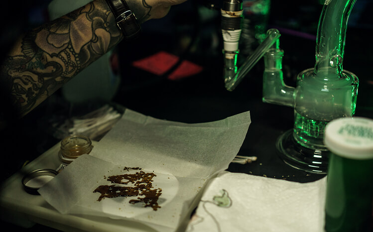 A woman getting ready to do a dab of cannabis shatter extract.