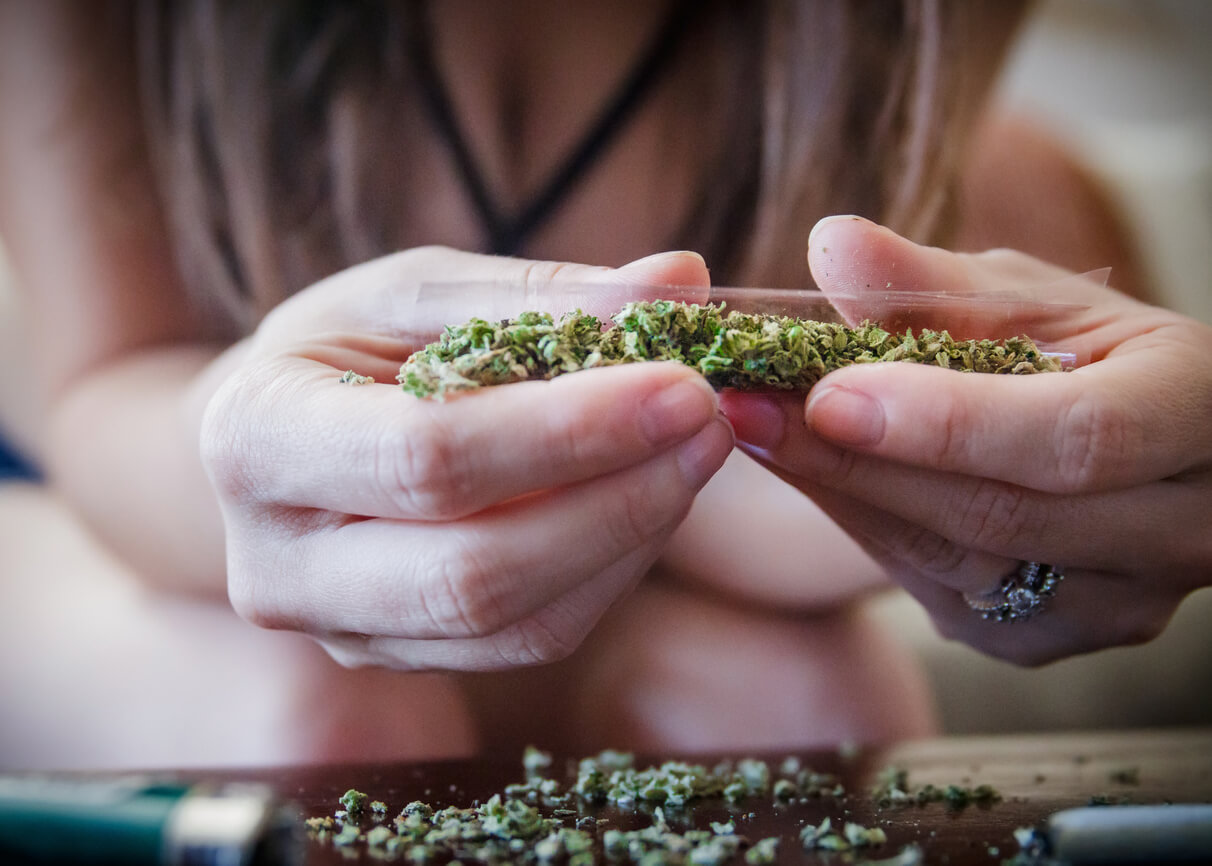 An anonymous woman holding a marijuana joint up-close.