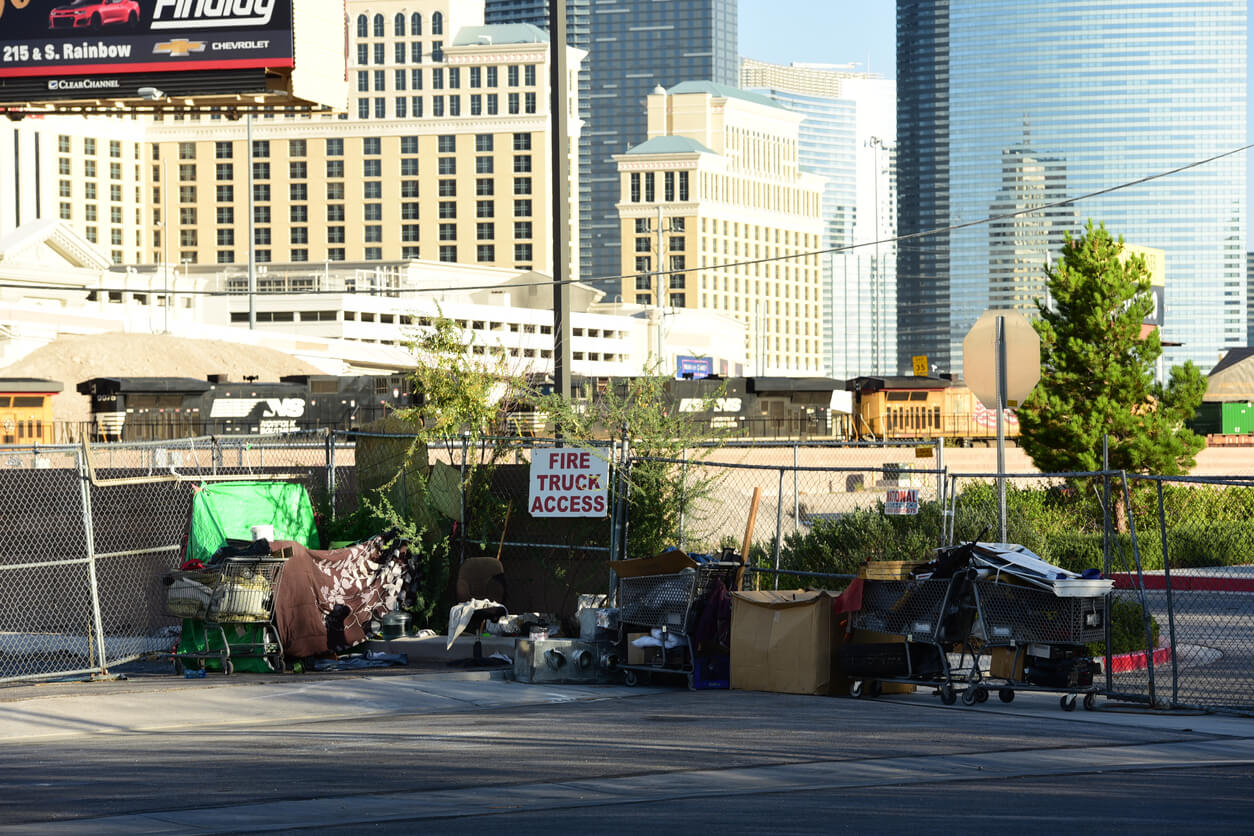 Shot of the Las Vegas Strip from behind. As a contrast to the gold and shine of The Strip Hotels and Casinos, we see how homeless people live on the street. Taken during a day.