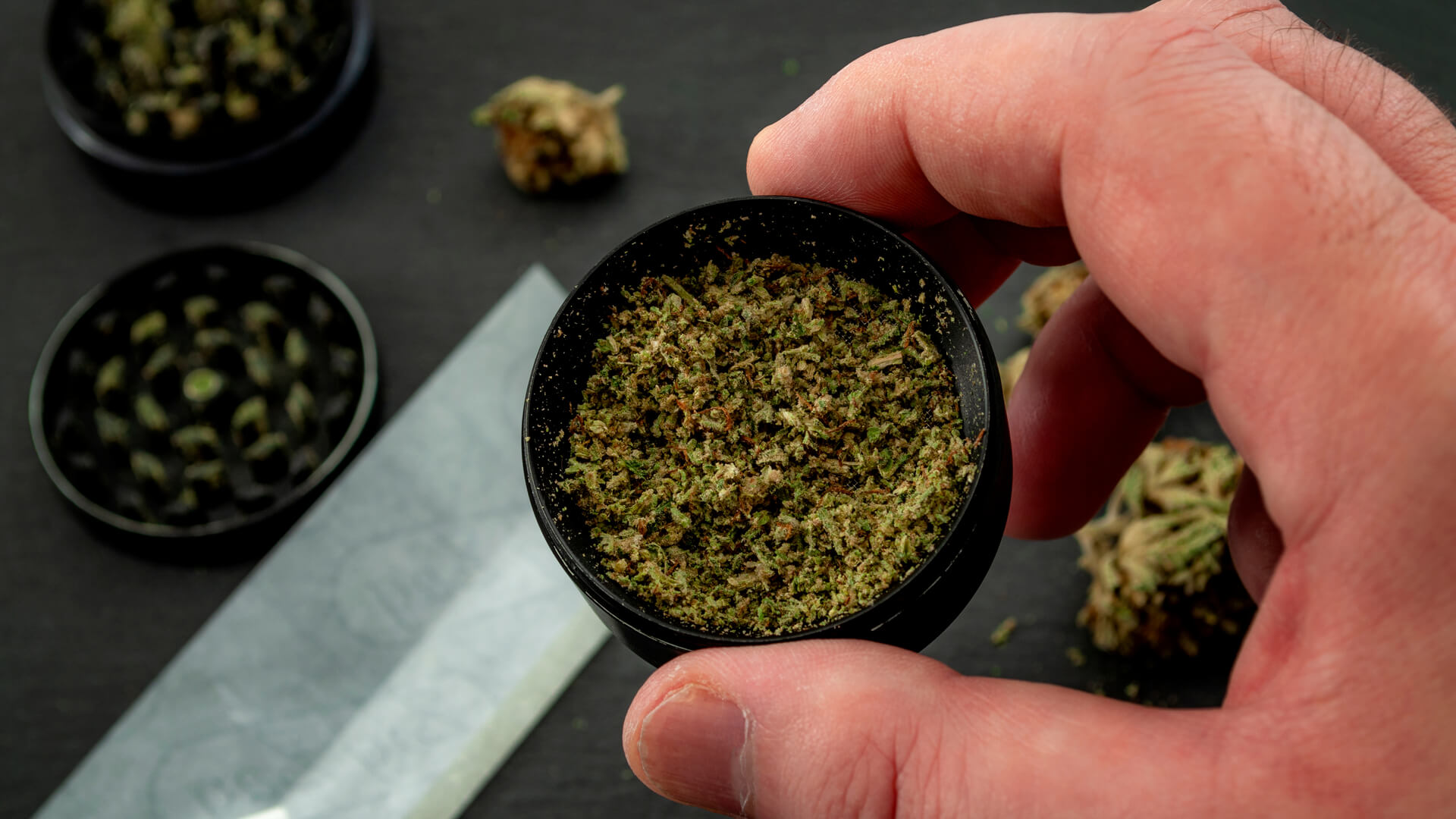 Hand holding a grinder with mid grade weed
