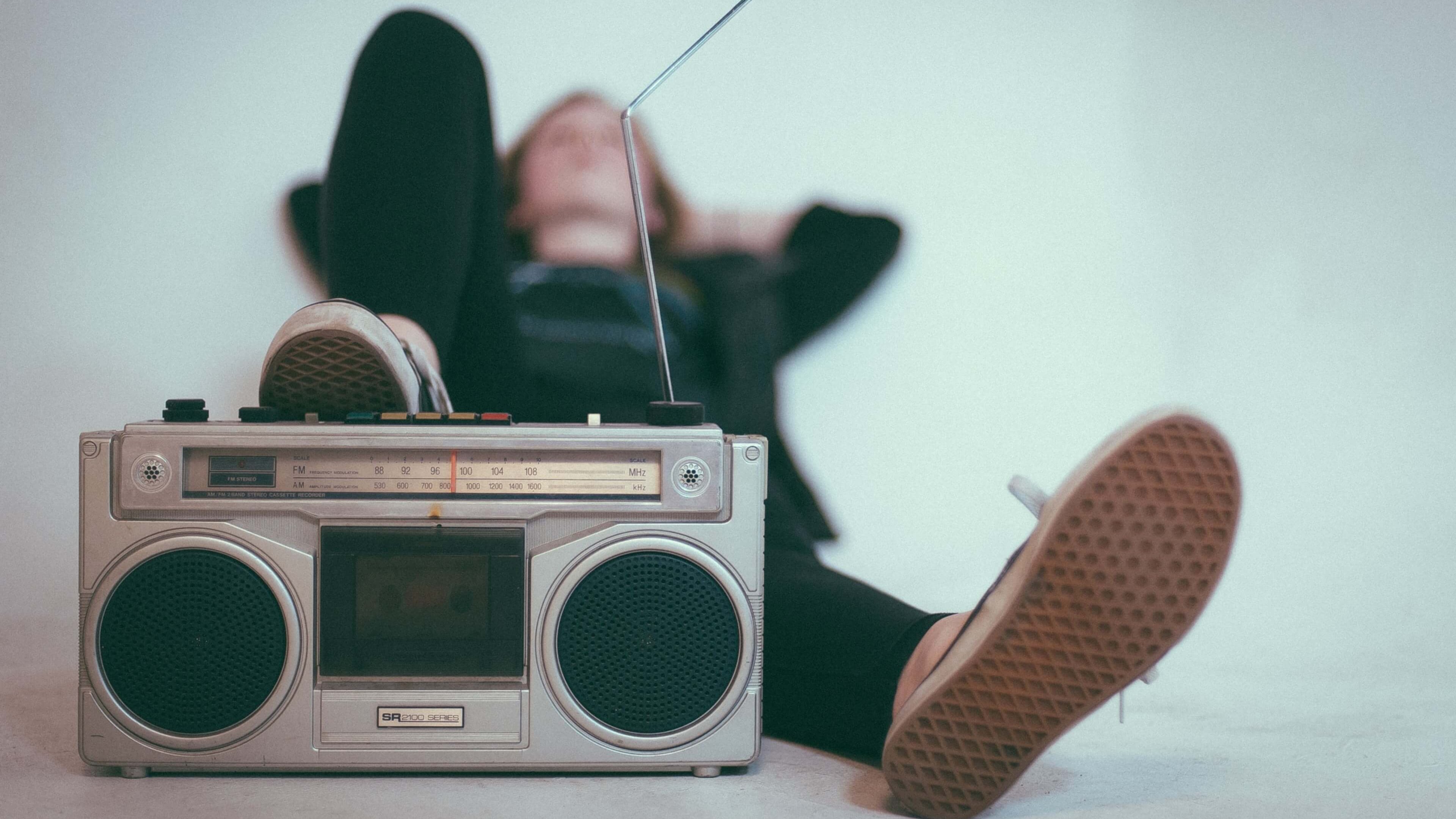 A blurry shot of a women reclining with sneakers on boombox