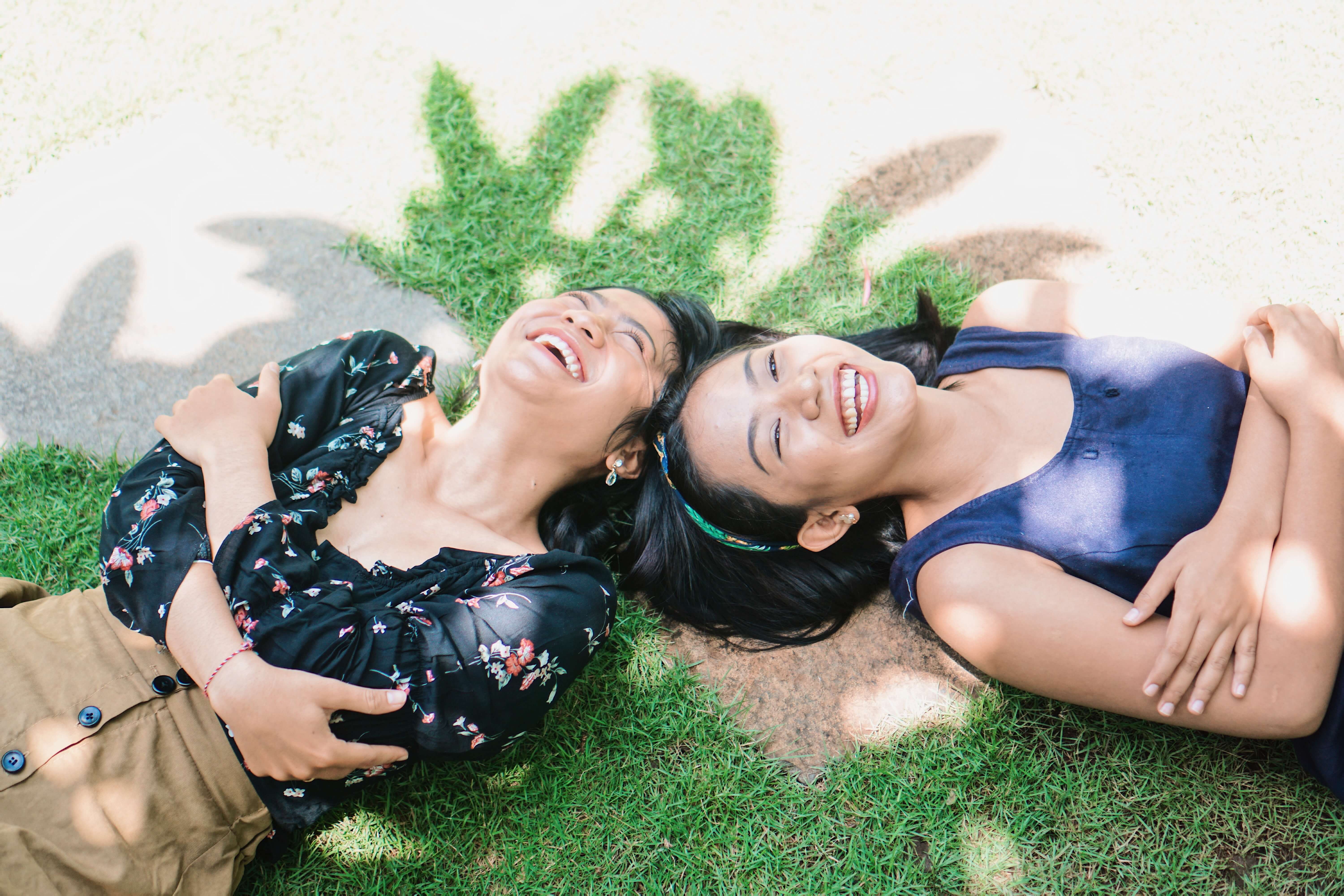 Two Girls laying down on grass smiling