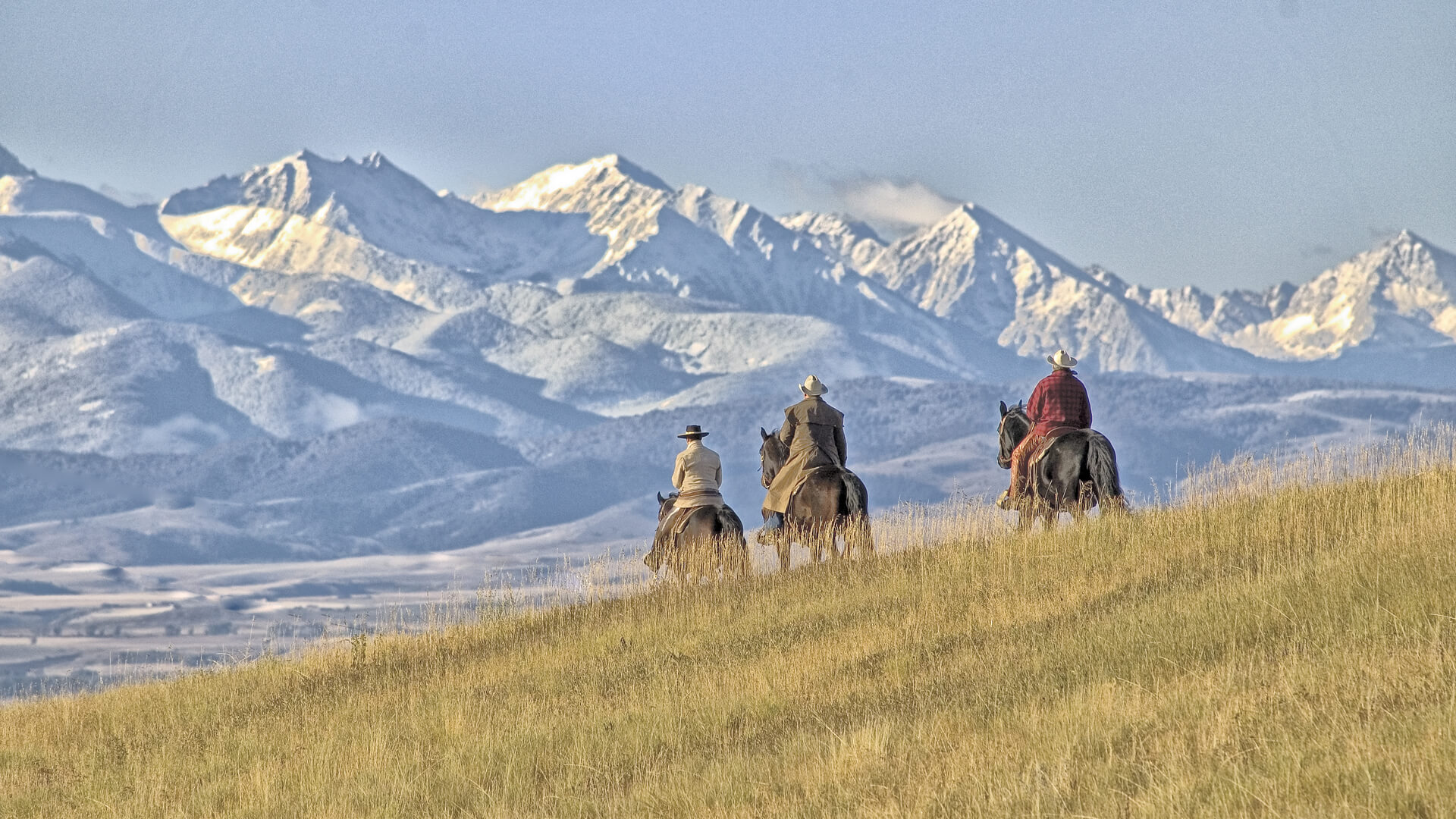 Cowboys riding on a Montana horse ranch with Mountains in the distance
