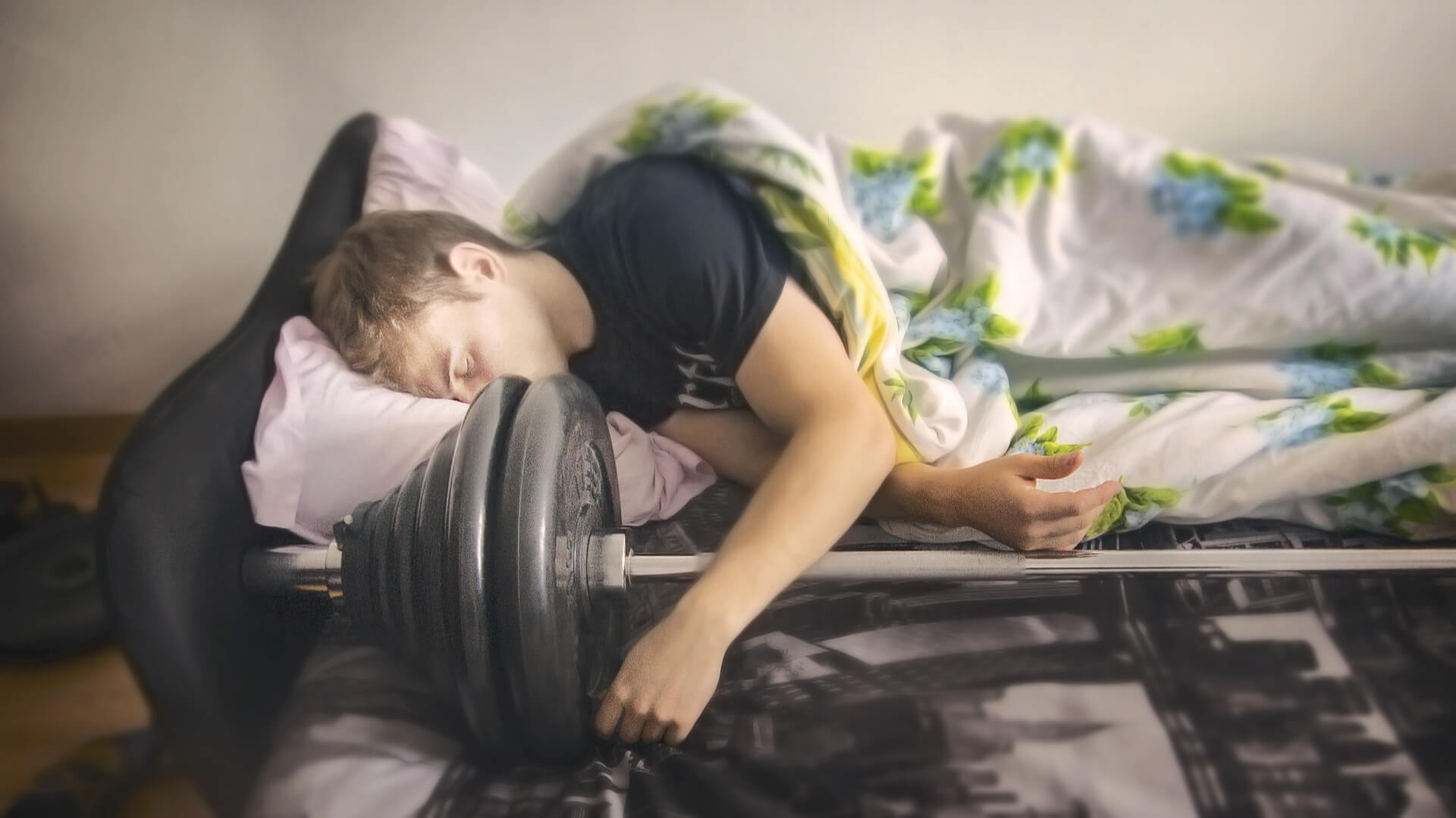 A bodybuilder guy sleeps with his athletic barbell after workout.