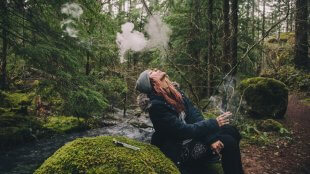 Blonde woman smoking cannabis while hiking in the woods