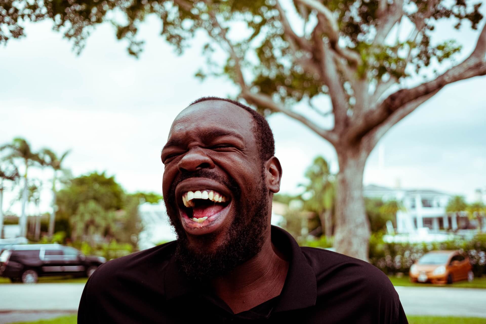 A portrait of a black man laughing on a sunny day