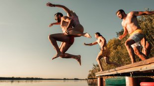 People jumping off a dock into a lake