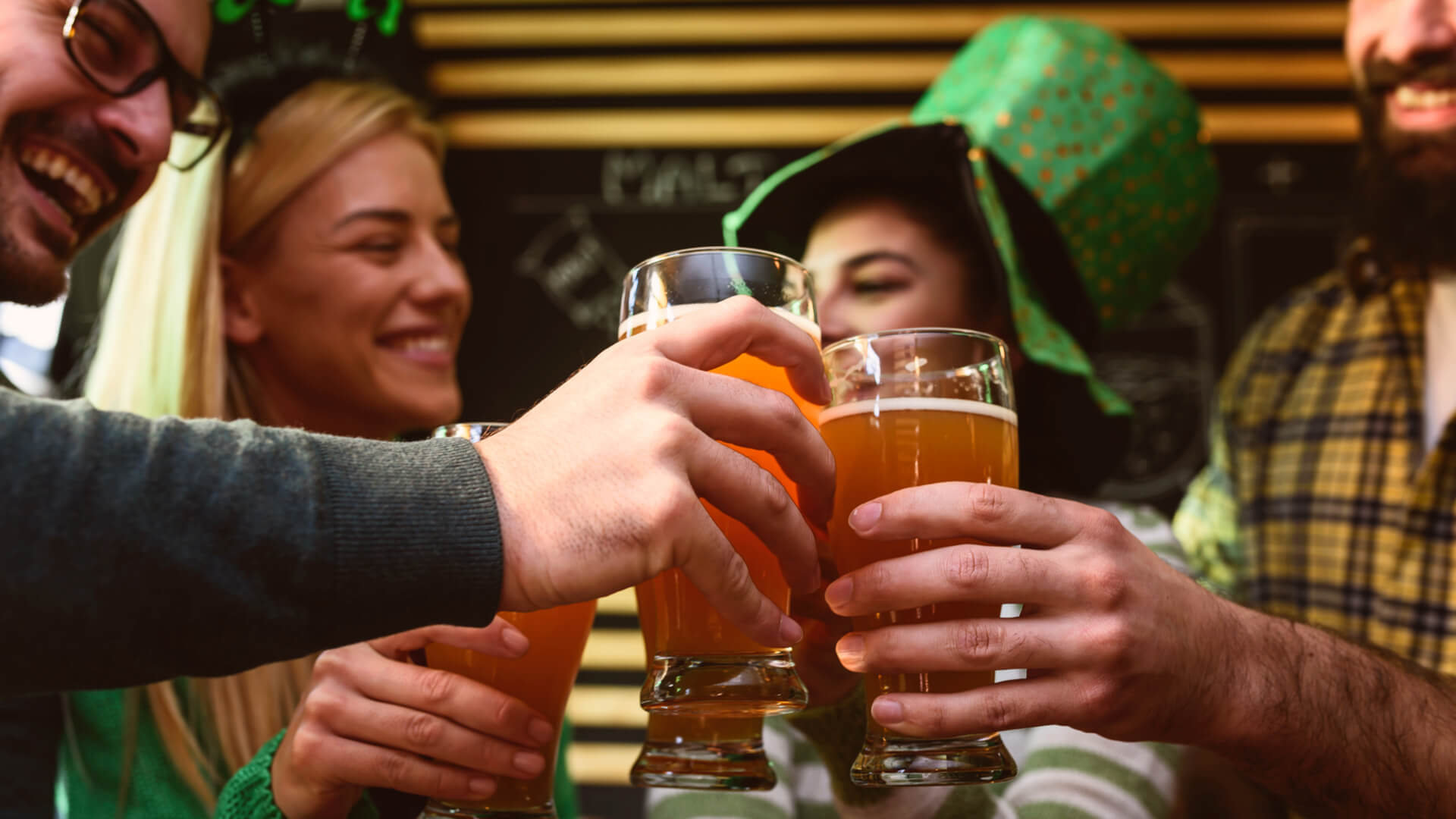 Group of friends celebrating St Patrick's Day toasting beer in a pub