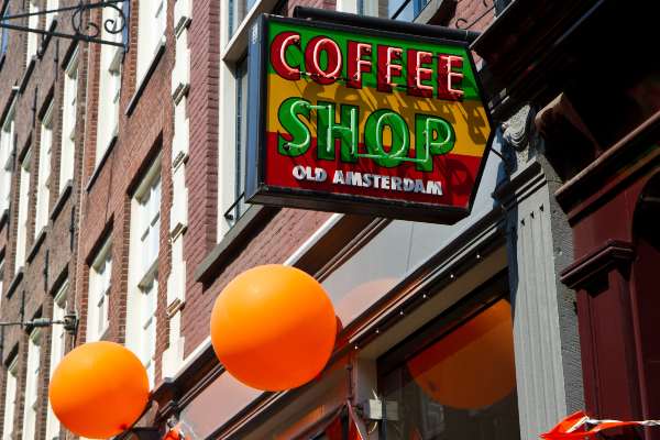 Amsterdam coffee shop with a green, yellow, and red with orange balloons on the building.