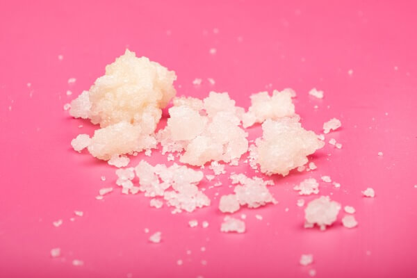 White cannabis concentrate crumbles on top of a pink background 
