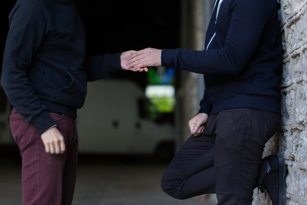 Someone shaking hands with another man, both wearing dark colors