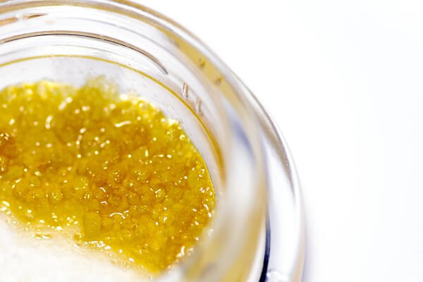Yellow cannabis hash oil that is in a clear jar.