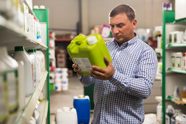 Man looking at a neon green pesticide bottle in a grocery store
