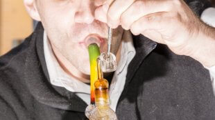 a man taking a dab from a traditional dab rig