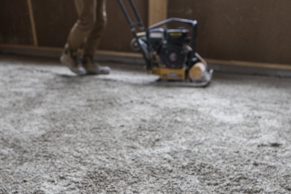 Man using a piece of machinery to smooth out grey hempcrete