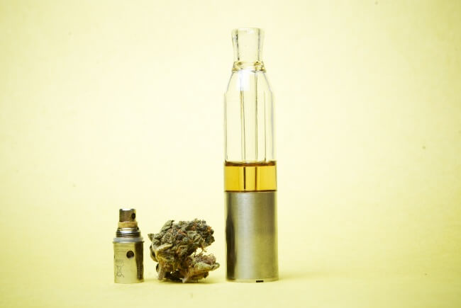 a delta 8 THC vape cartridge next to a bud of cannabis