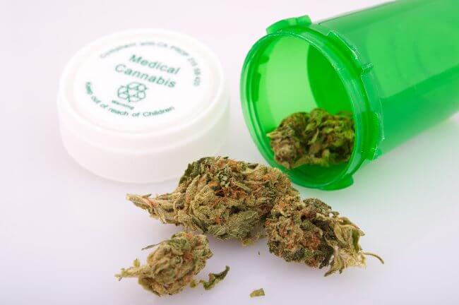 cannabis nugs spilling out of a green medicinal cannabis container