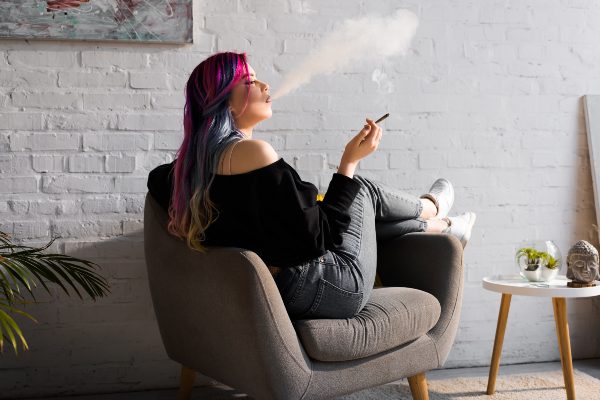 Girl smoking a joint in a chair inside apartment
